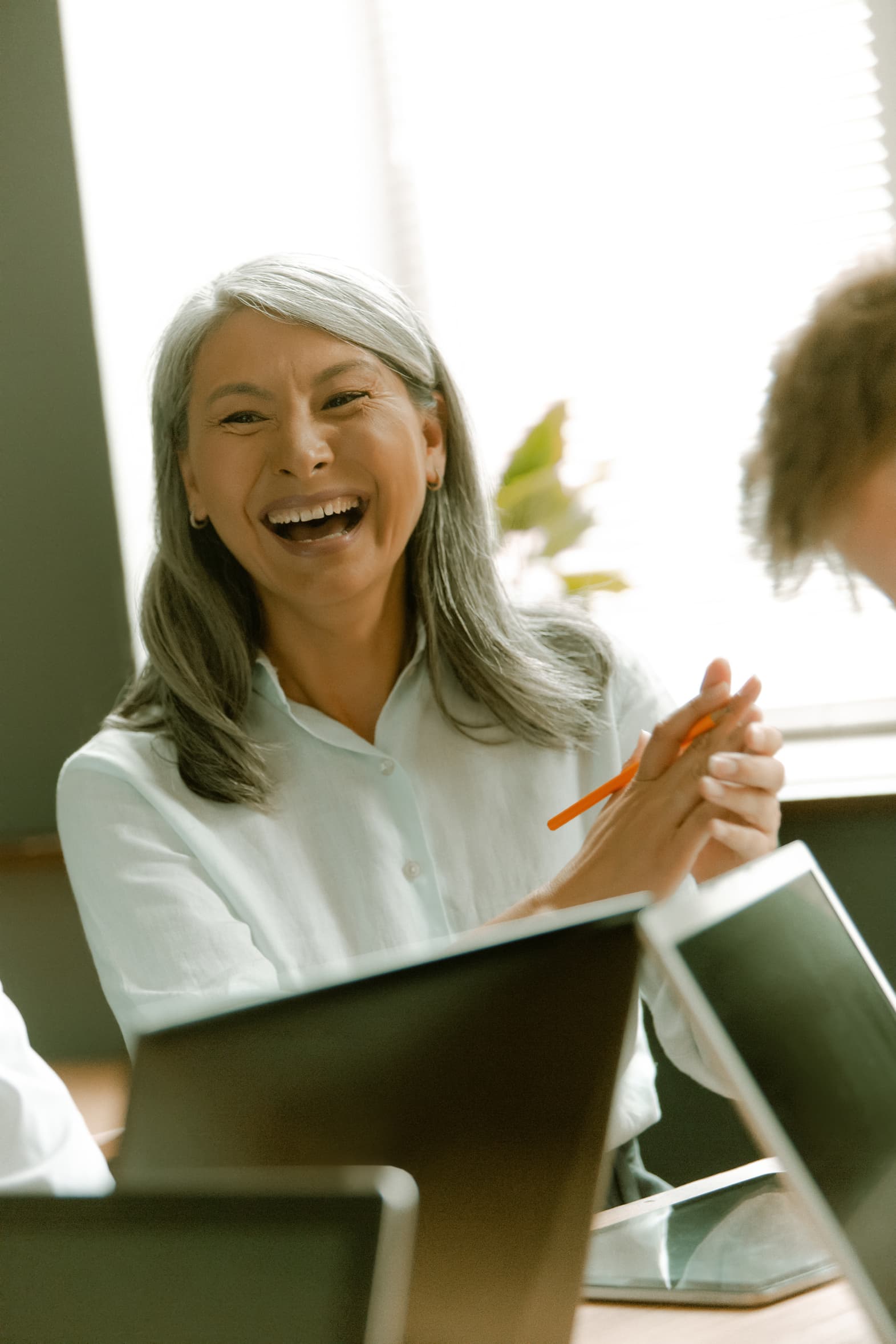 A senior woman laughing during a business meeting