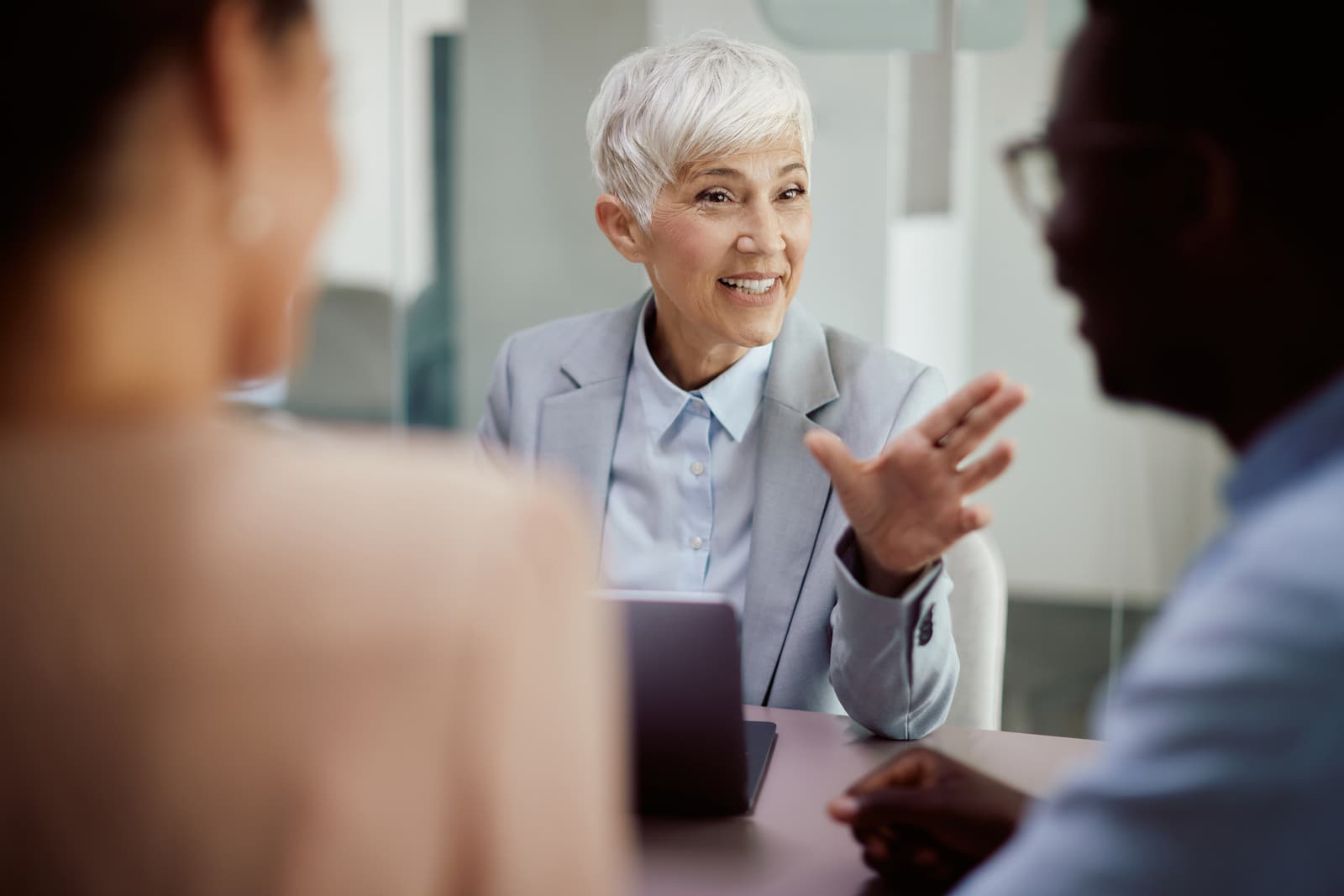 Happy mature insurance agent on meeting with her clients in office
