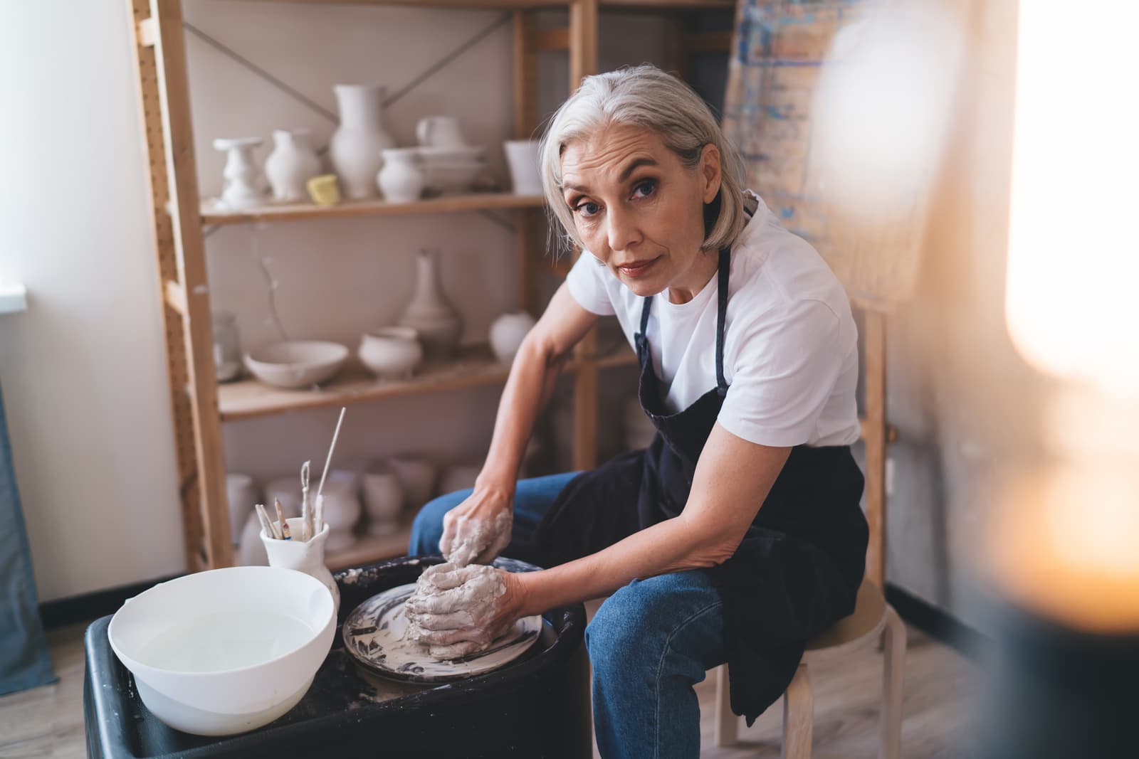 Female sculptor making clay pot on pottery wheel