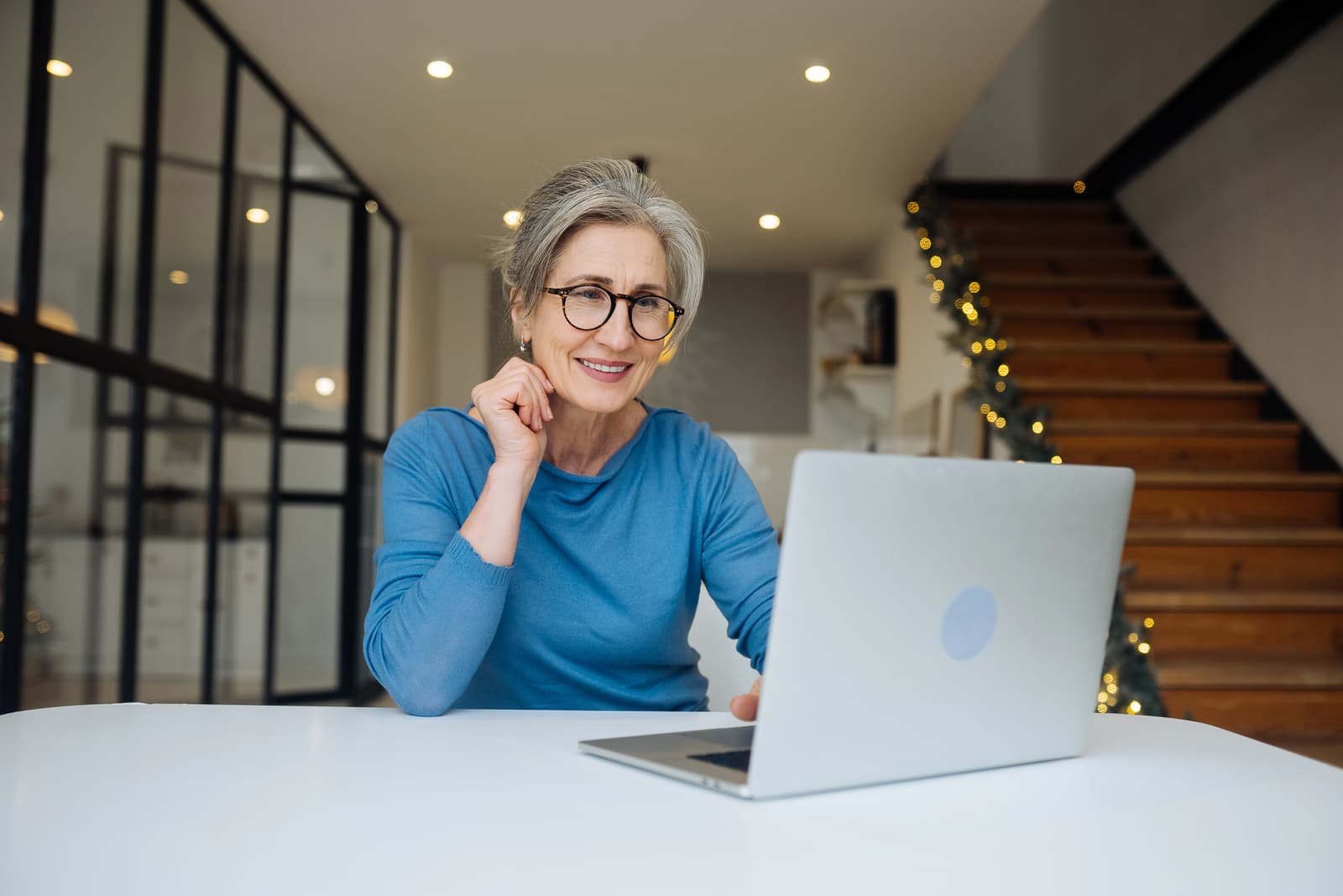 Happy mature middle aged elderly woman looking at laptop
