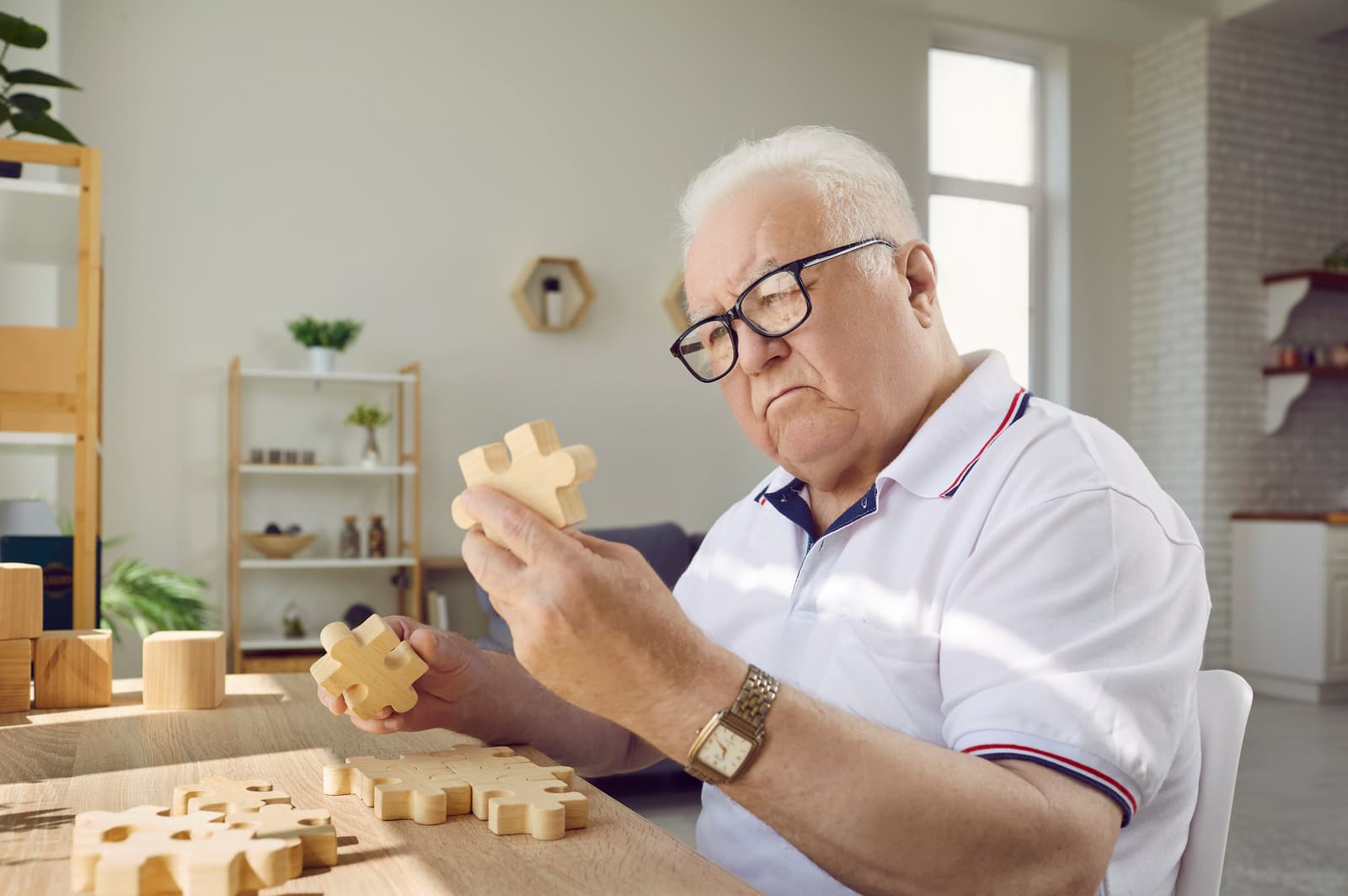 Senior man playing with jigsaw parts