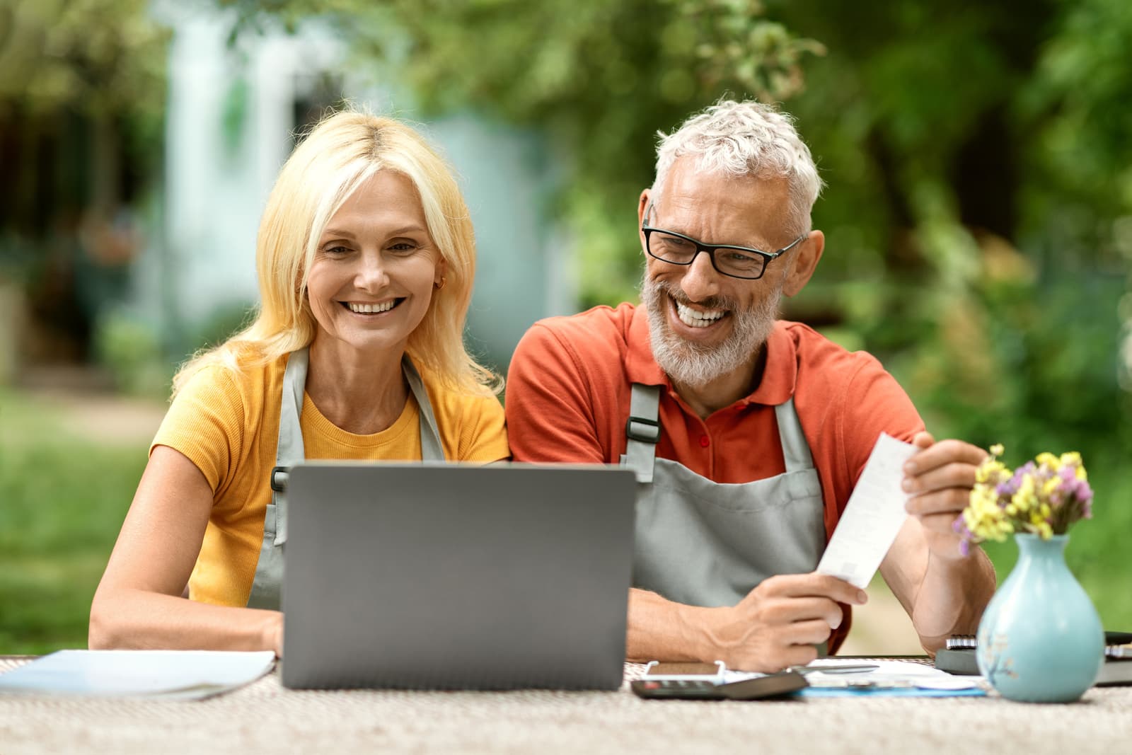Happy senior couple using laptop outdoors in their garden