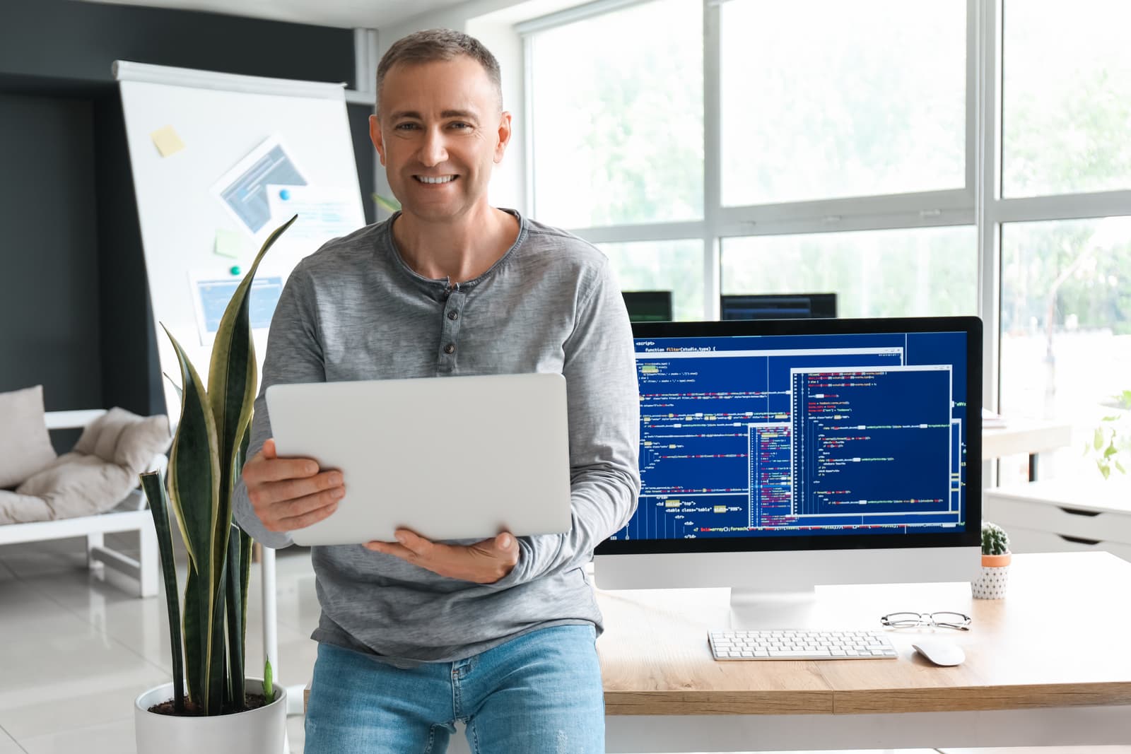 A mature software founder working on his laptop in a bright office