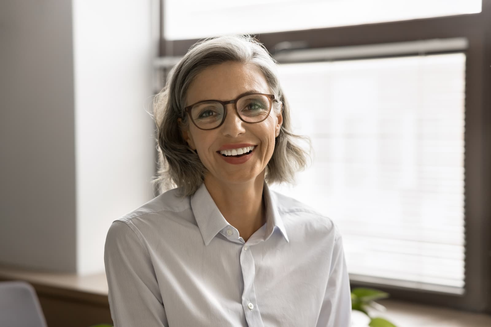 Head shot close up profile picture of beautiful middle-aged businesslady posing in workplace, smiling, look at camera, f