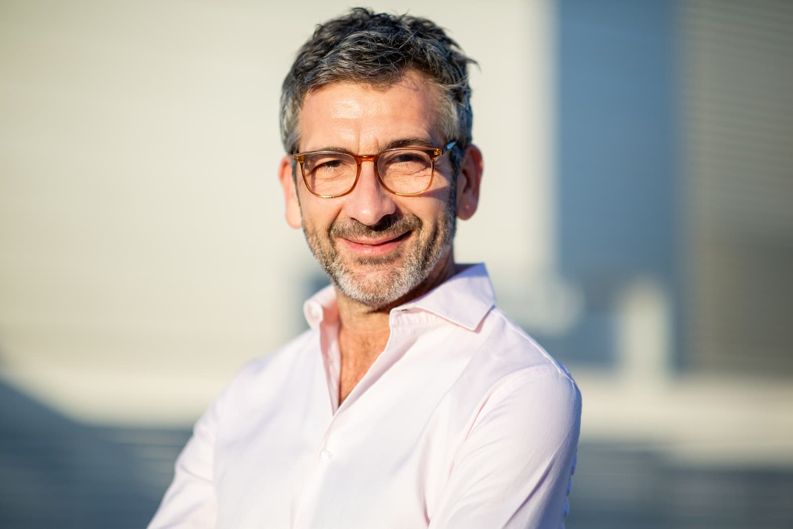 Confident man in white pink shirt and glasses smiling outdoors