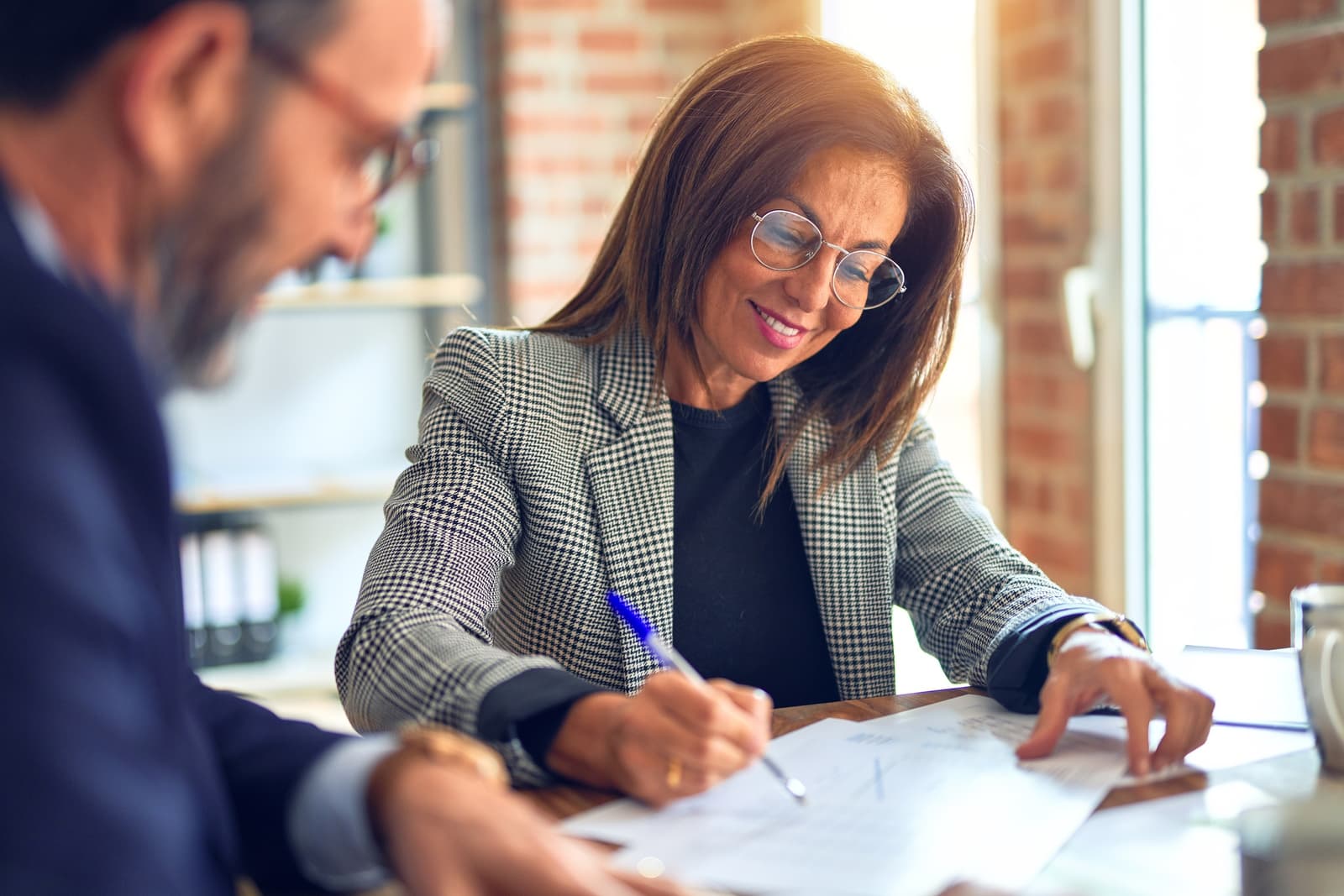 Two business people in their fifties smiling in an office
