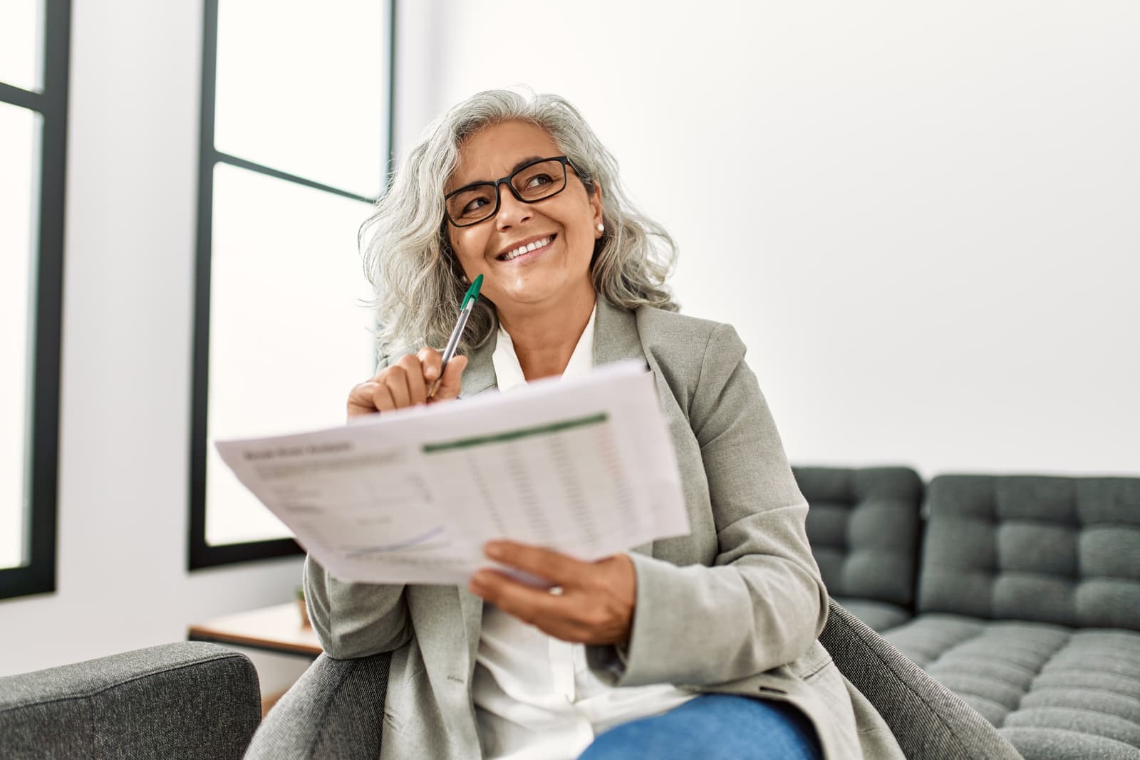 A grey-haired businesswoman smiling as she reads