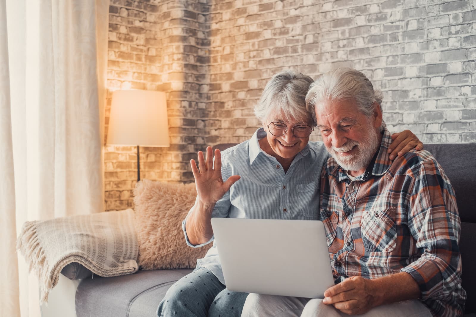 Cute couple of old people sitting on the sofa using laptop together shopping and surfing the net