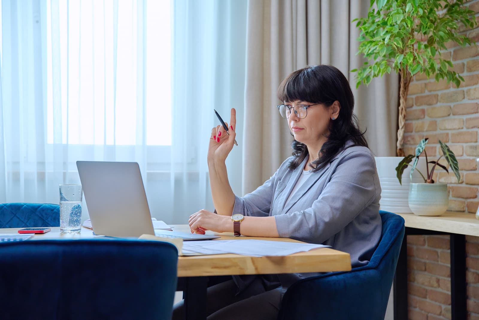 Mature business woman at workplace using laptop for virtual video meeting