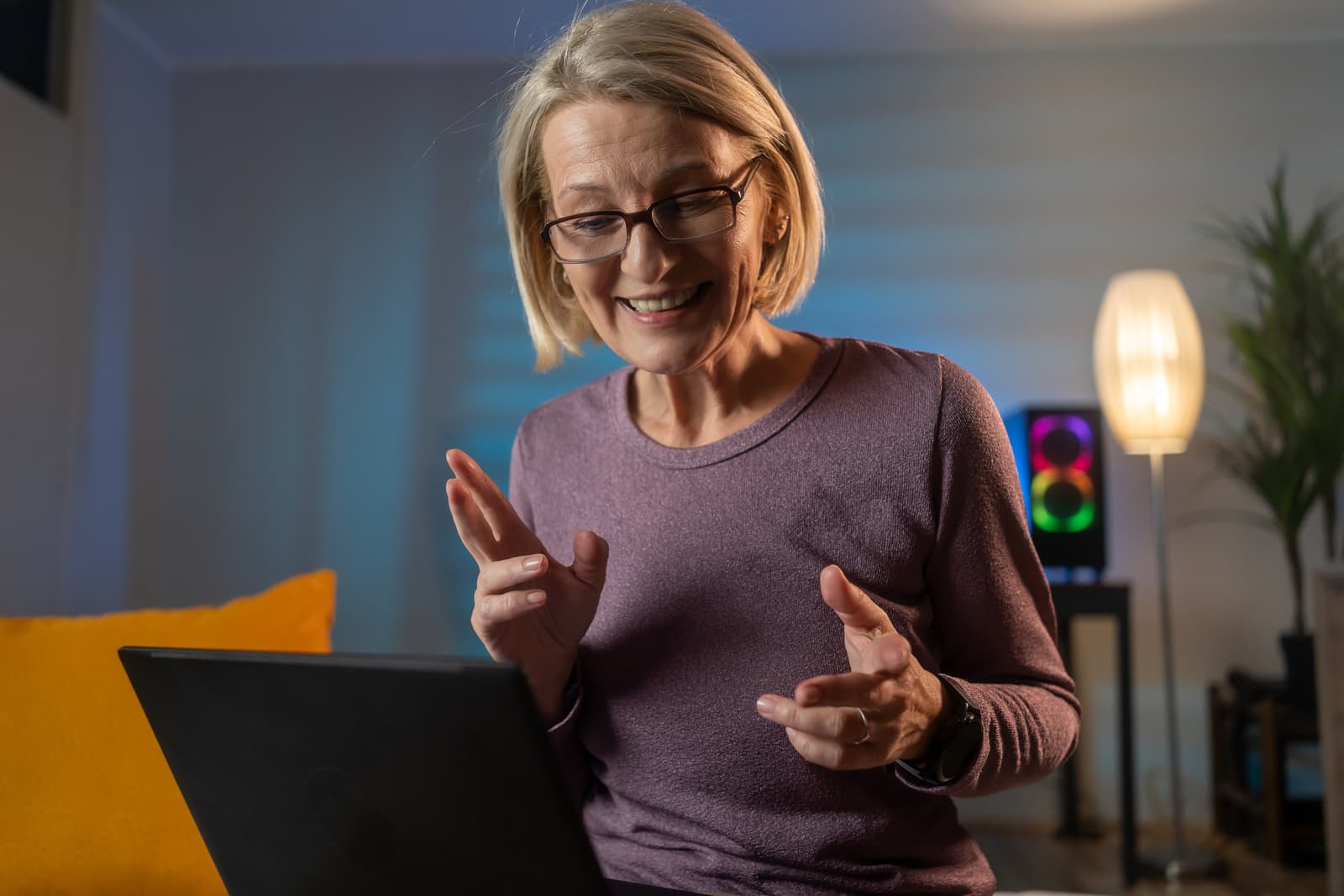 Happy casual beautiful mature woman working on a laptop, talking with somebody in office