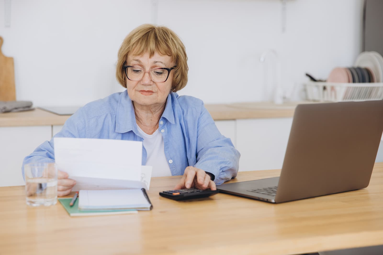 Senior business woman holding paper bill using calculator, old lady managing account finance, calculating money
